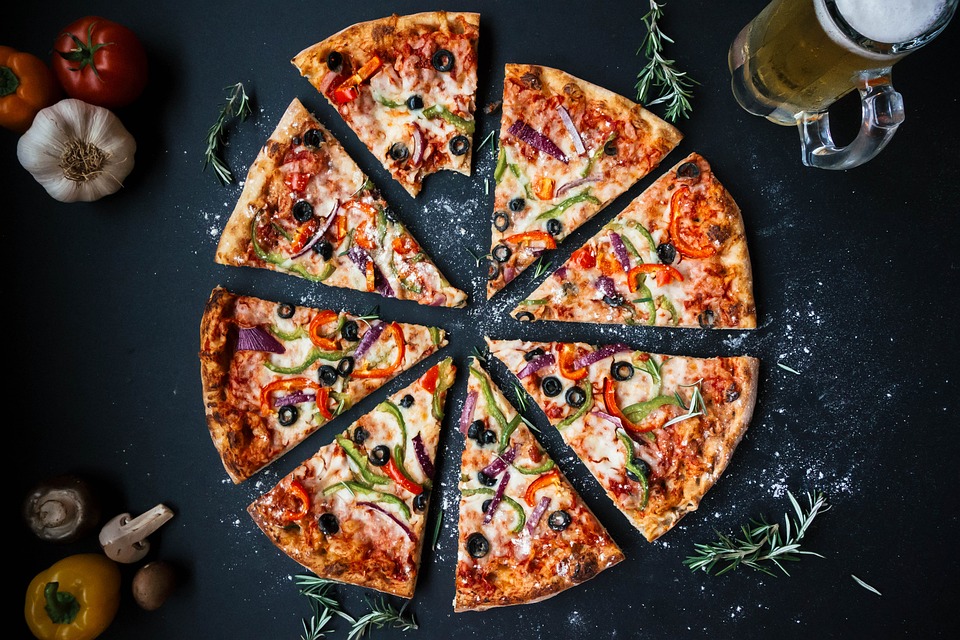 Image of a pizza cut into slices, with a bite taken from one slice.