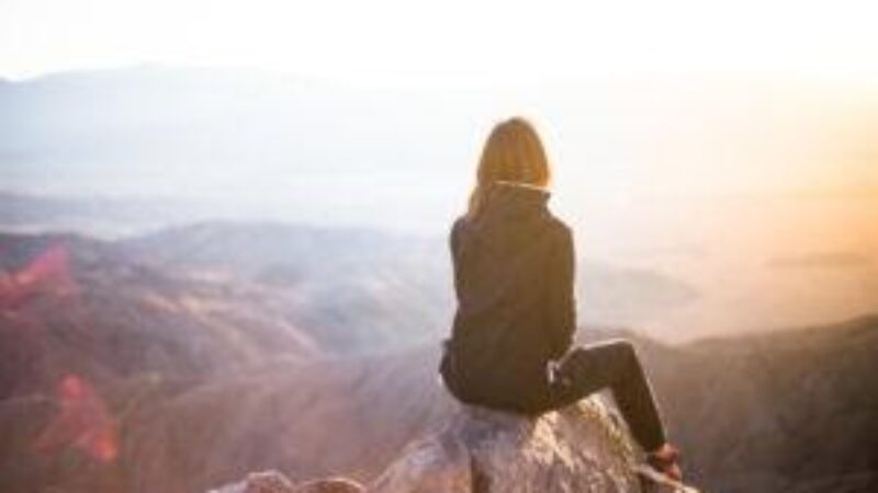 a woman sitting on top of a mountain