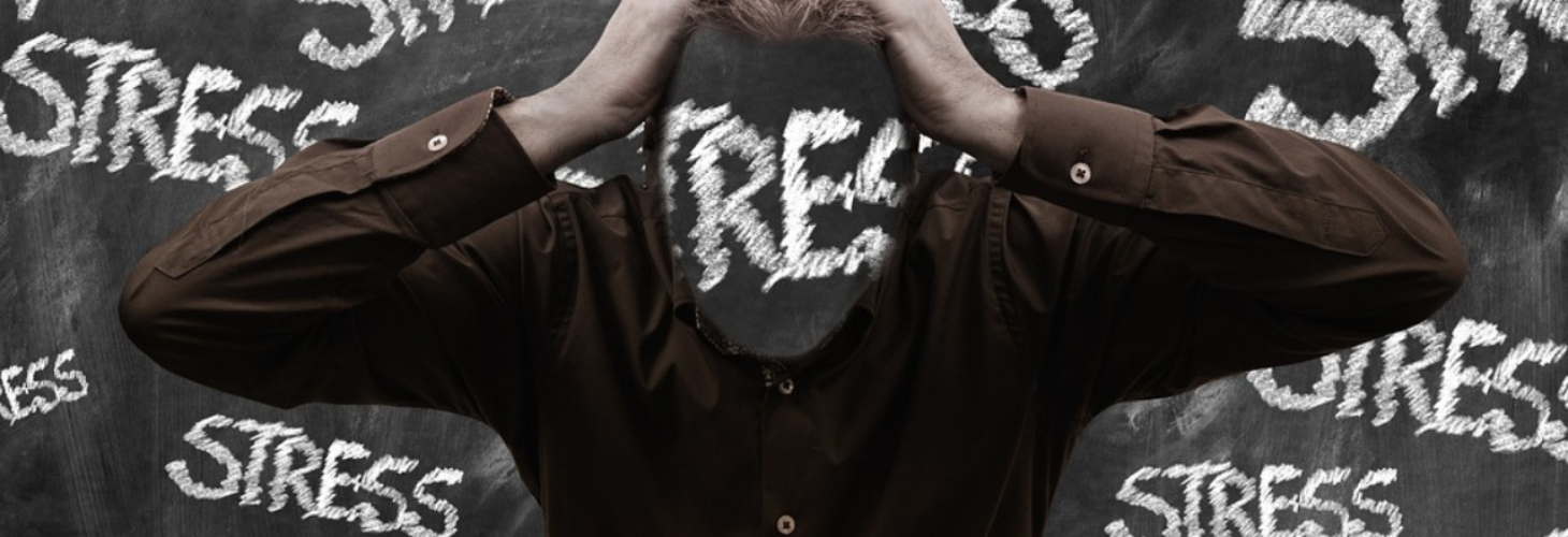 A person surrounded by the words stressed with their head in their hands.