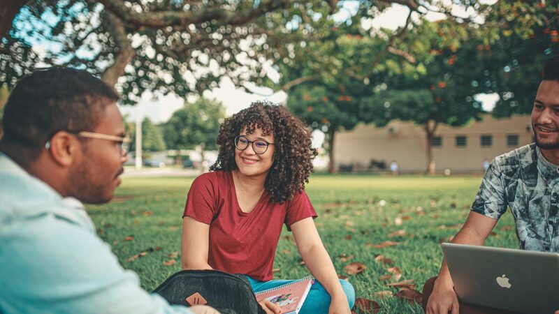 3 students sat out on a campus green.