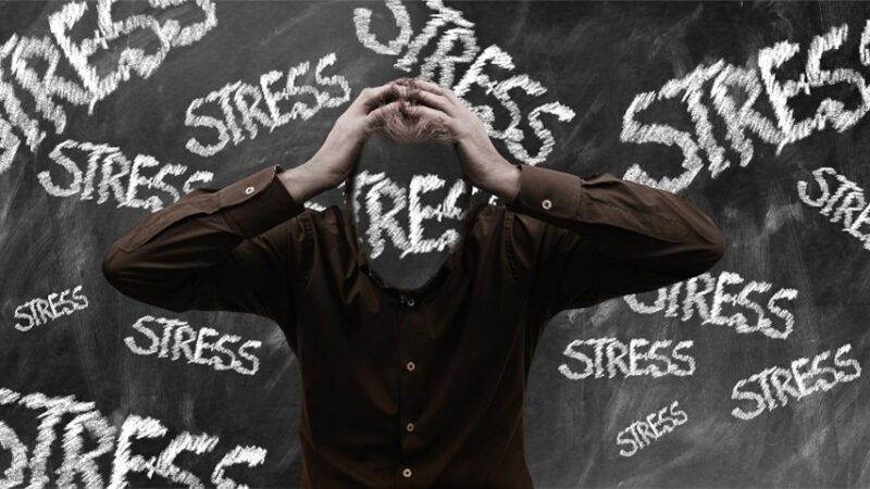 man holding his head with stress around him