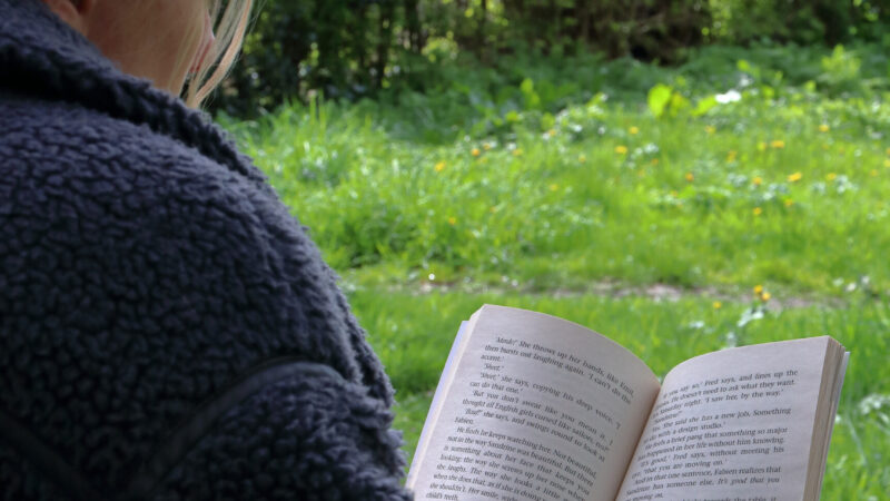 woman reading a book on the grass